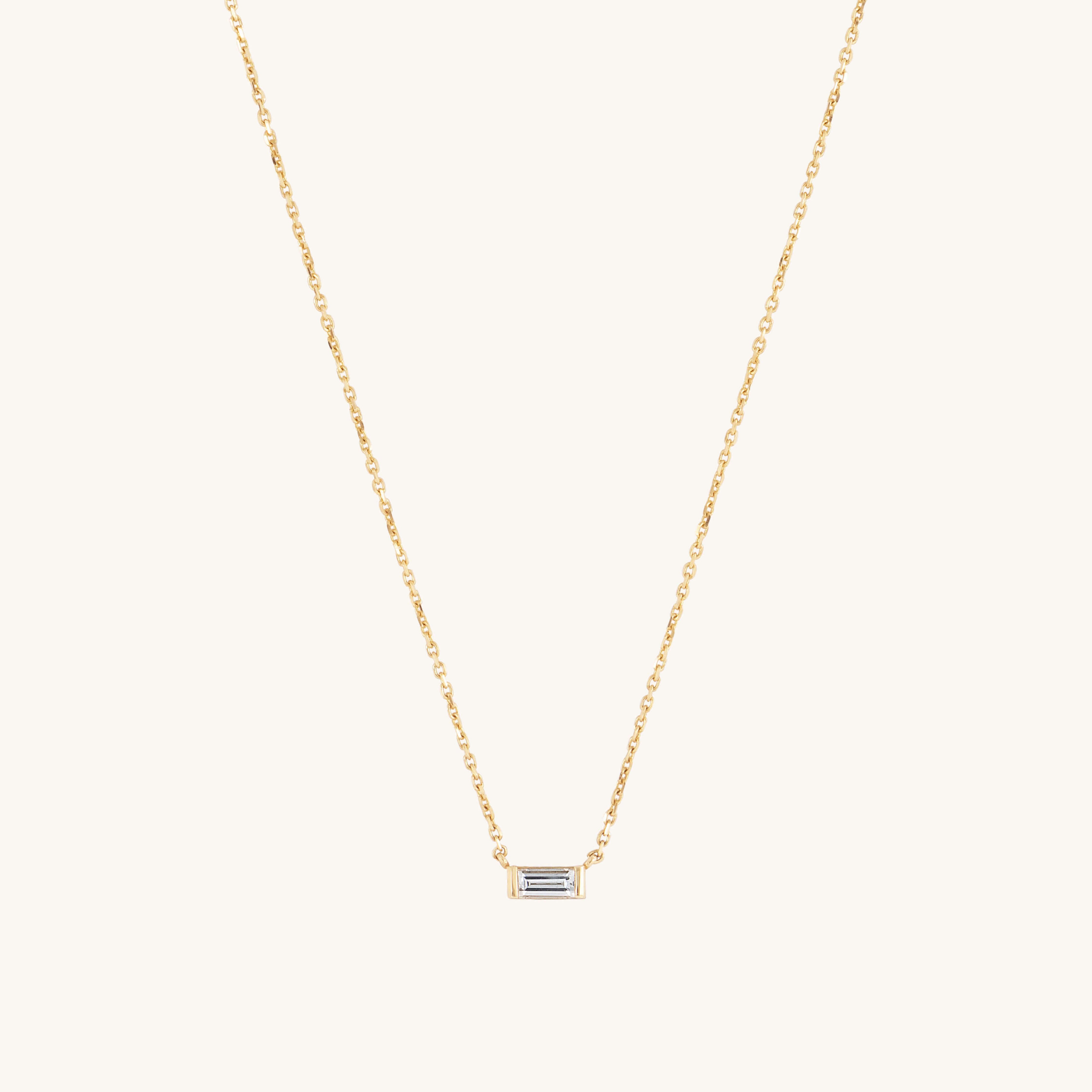 The Siglo Necklace by Glasâje showcases a delicate 9ct solid gold chain and a small rectangular baguette-cut ethically-grown diamond pendant, elegantly set against a plain white background.