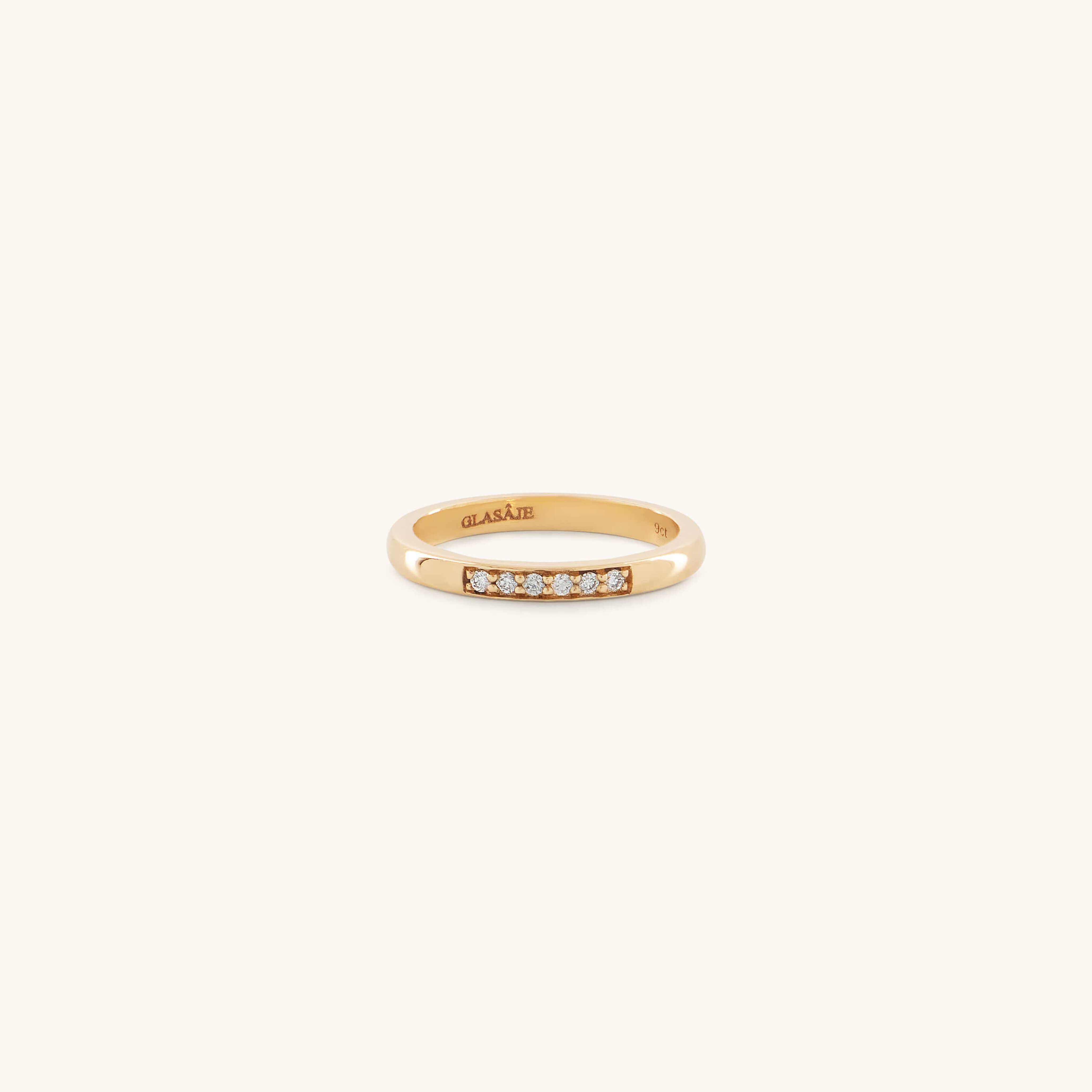 A gold ring with a minimalist design features a row of six small, sparkling diamonds. The setting is simple yet elegant, conveying a timeless charm.