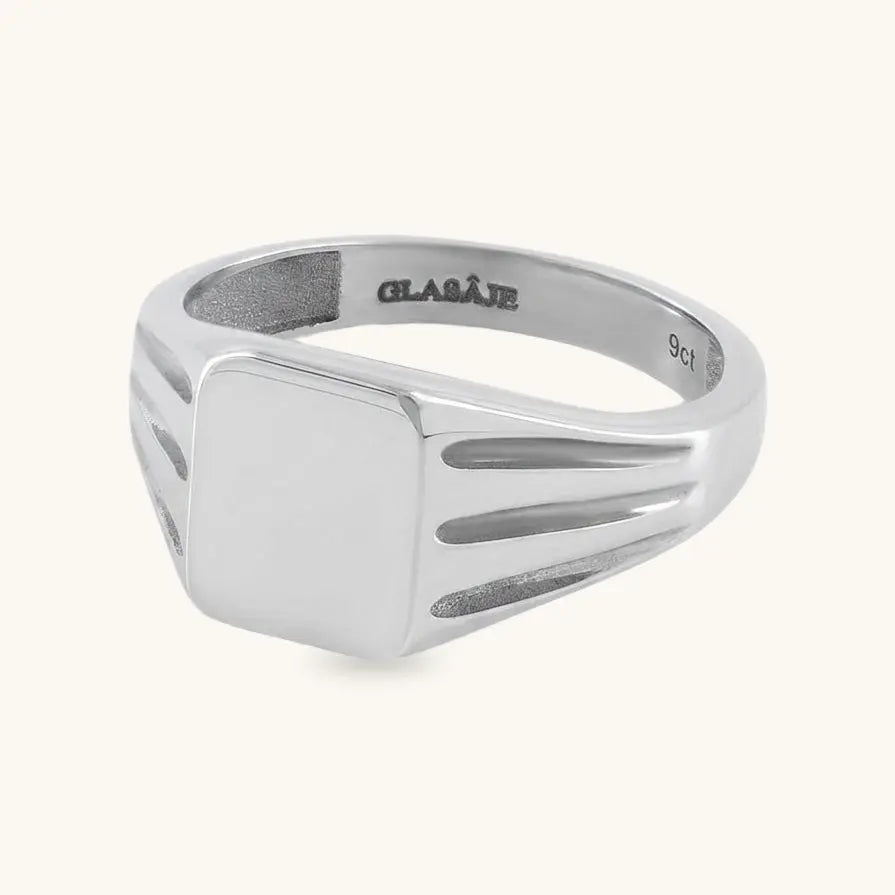 A silver signet ring with a flat square face and parallel channel details on the shoulders, shown on a light cream background. The inside of the band is engraved with the brand name 'GLAIVE' and '925'.