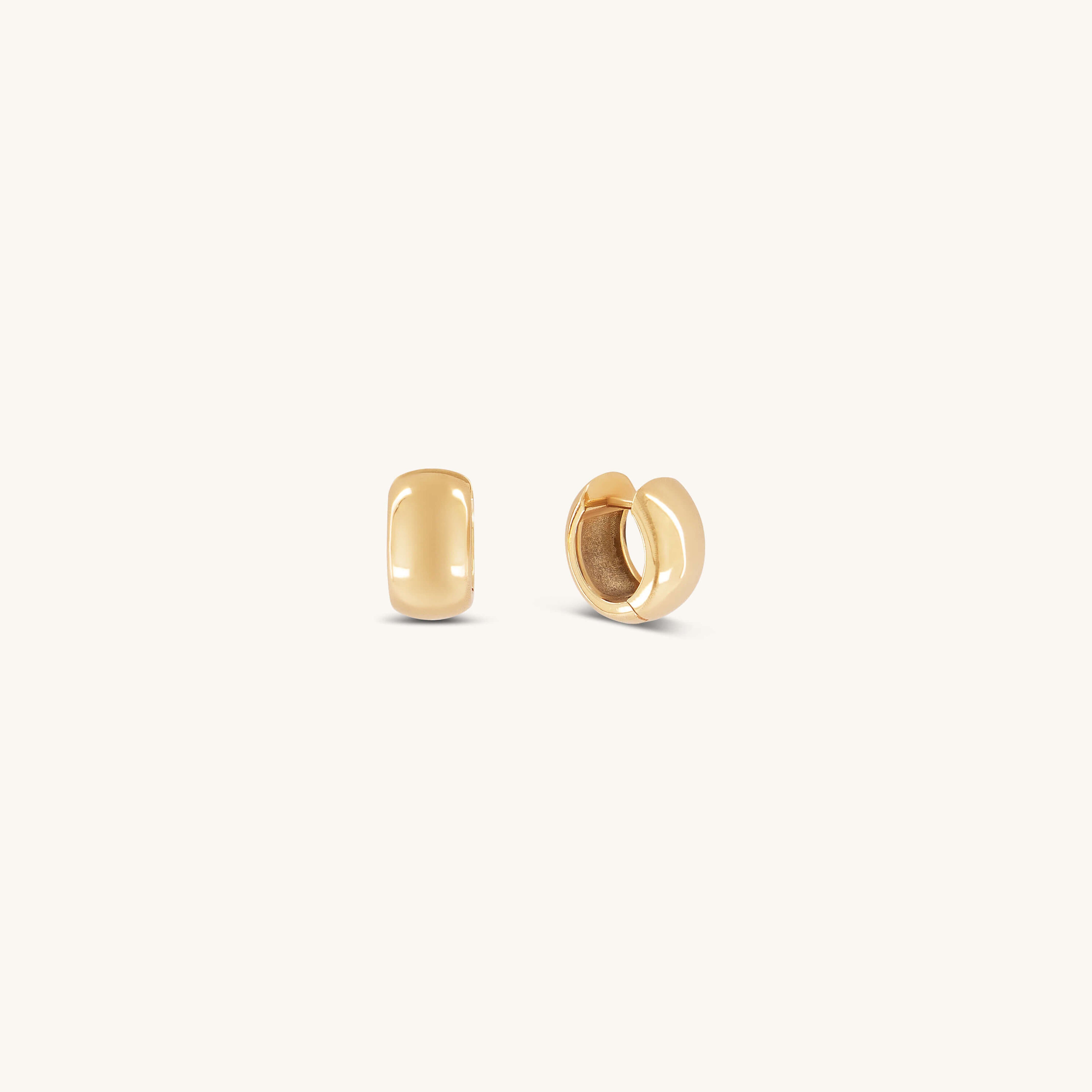 Two small, smooth Gabriel Huggies from Glasâje are displayed on a light beige background—one shown from the front and one from the side—offering an effortless, timeless staple for any jewelry collection.