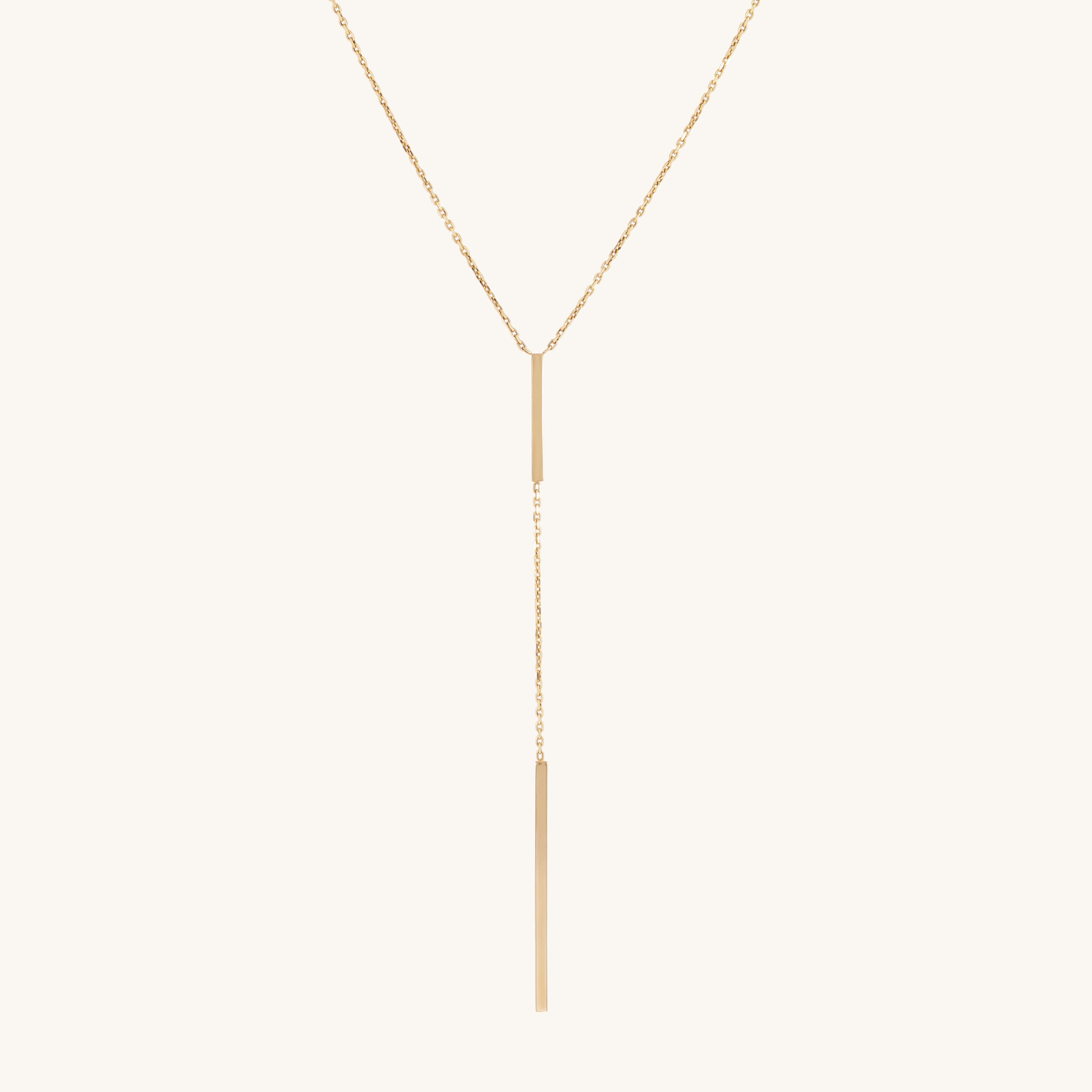 Elegant gold lariat necklace with a thin vertical gold bar pendant, dangling gracefully. The sleek design conveys simplicity and sophistication.