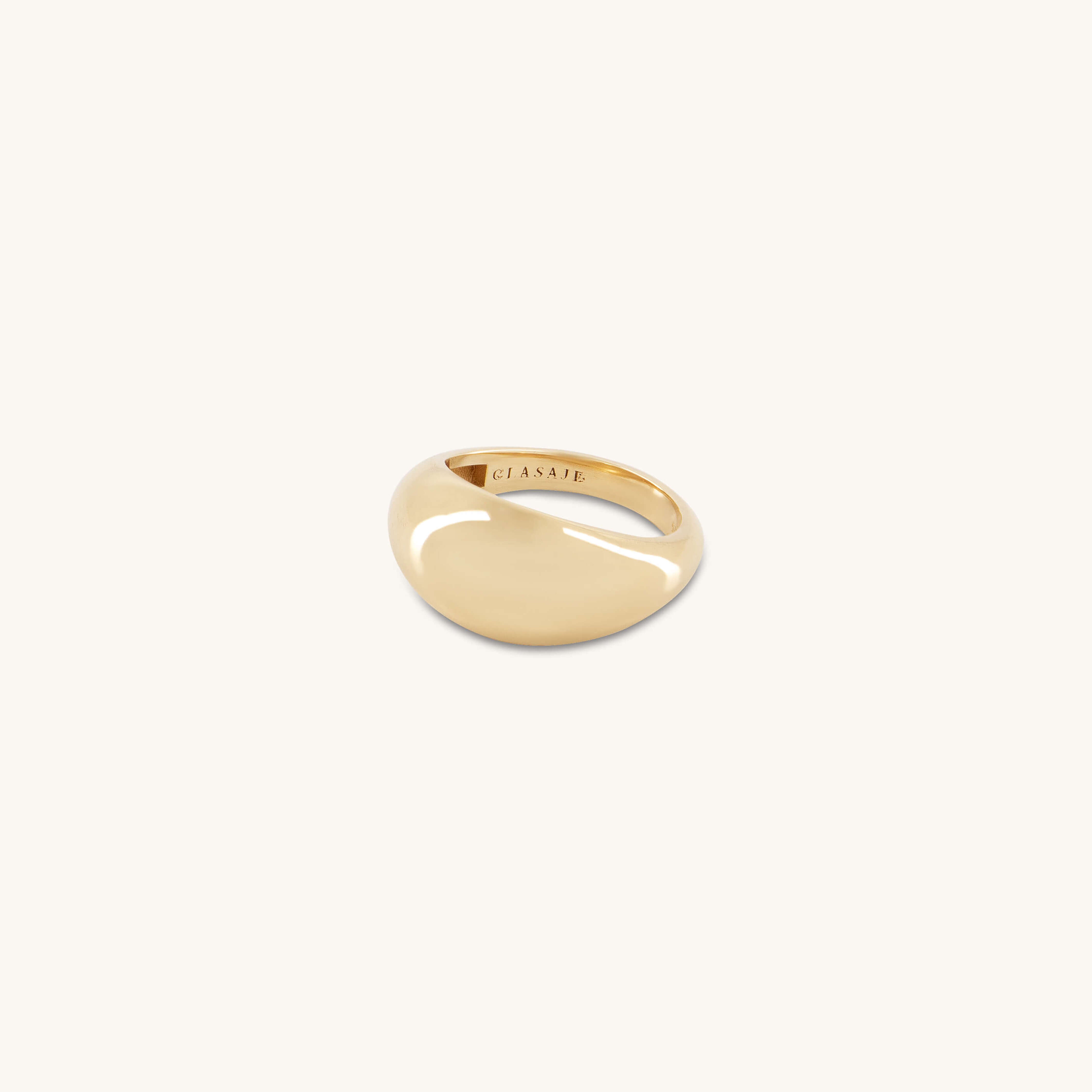 The Glasâje Dôme Ring, crafted in polished solid gold with a smooth, oval top, is displayed centered on a plain off-white background.
