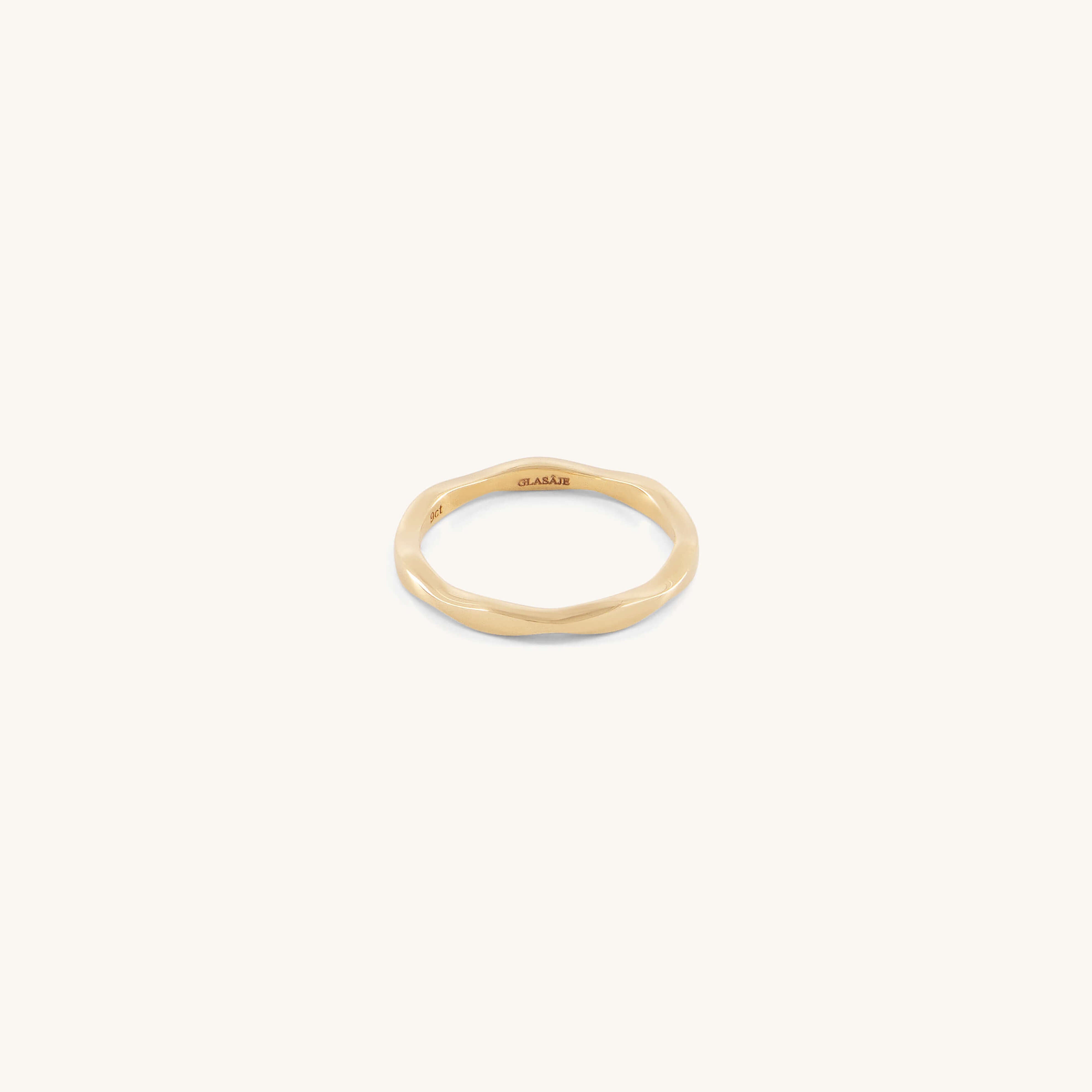 The Glasâje Ripple Stacking Ring is a slender 9ct solid gold band featuring an organic, wavy ripple design, shown against a plain, light background.