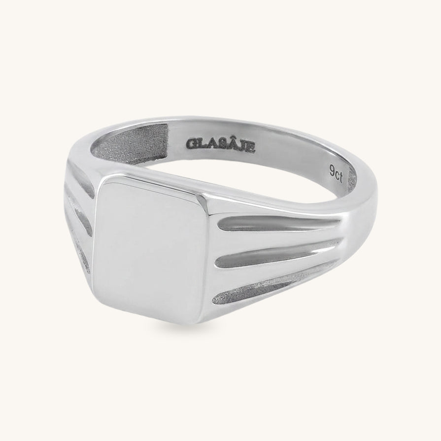 A silver signet ring with a flat square face and parallel channel details on the shoulders, shown on a light cream background. The inside of the band is engraved with the brand name 'GLAIVE' and '925'.